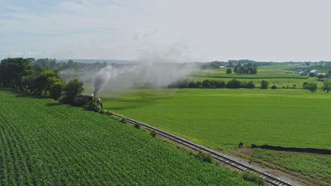 Eine-Luftaufnahme-Der-Landschaft-Von-Pennsylvania-Mit-Einer-Einzigen-Dampfmaschine,-Die-Sich-An-Einem-Sommermorgen-Mit-Rauch-Und-Dampf-Nähert