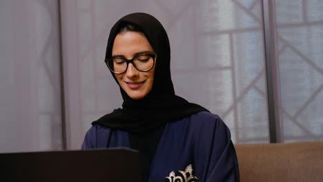 Online-video-conferencing-of-Arabic-Emirati-woman-wearing-eye-glasses,-traditional-UAE-Abaya-and-Hijab