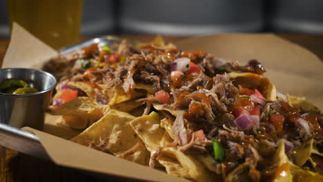 Nachos-piled-high-with-queso-cheese-pulled-pork-carnitas-and-salsa,-slider-4K