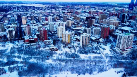 Aerial-hold-over-Downtown-Edmonton-Victoria-Park-Edge-on-a-winter-day-birds-eye-view-over-the-high-rises-of-apartments-and-condominiums-with-snow-covered-trees-realty-properties-for-rent-or-for-sale
