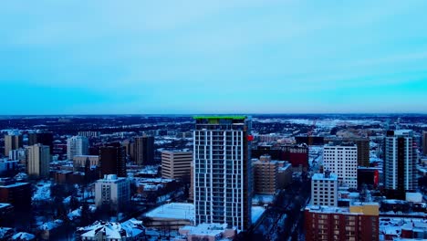 Winter-Construction-condominium-apartment-tower-almost-complete-with-fluorescent-red-orange-service-elevator-on-the-outside-rising-up-to-the-top-floor-facing-the-south-West-view-of-downtown-Edmonton