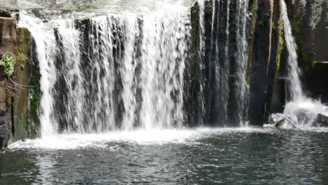Panning-shot-of-splashing-Kerikeri-Waterfall-during-sunny-day-in-summer-in-New-Zealand