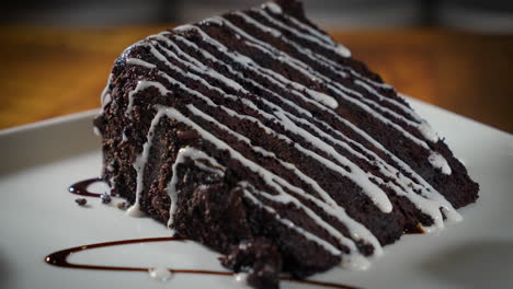 Dekadenter-Schokoladenkuchen-Mit-Drei-Schichten,-Beträufelt-Mit-Glasur-Auf-Weißem-Teller,-4k