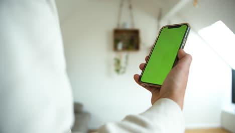 Slow-motion-shot-of-a-man-holding-smartphone-with-green-screen-moving-in-white-isolated-background