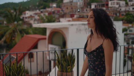 Young-woman-on-a-rooftop-with-a-tropical-town-in-the-background---focus-rack-from-the-village-to-the-girl