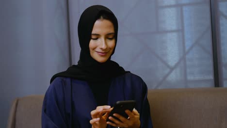 Female-wearing-Hijab-Abaya-using-smart-mobile-cell-phone