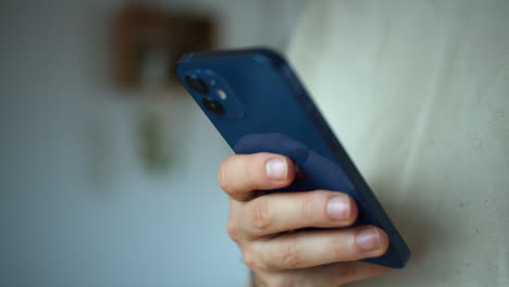 Back-view-of-a-smartphone,-a-man-holding-blue-smartphone-and-chatting-in-it-standing-in-white-background