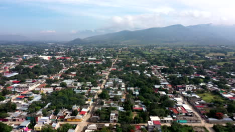 Aerial-view-of-the-suburbs-of-the-city-of-Oaxaca-in-Mexico,-filmed-by-a-drone-with-horizontal-displacement-in-a-crowded-area-and-skyline-in-the-background