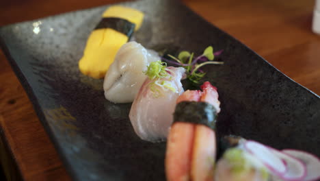 Plato-Tradicional-De-Sushi-Sashimi-En-Restaurante-Japonés,-Variedad-Colorida-De-Nigiri,-Control-Deslizante-De-Cierre-4k