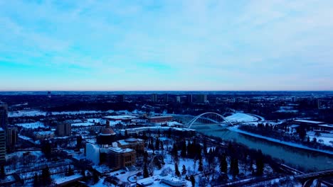 Winterluftaufnahme-über-Dem-Schneebedeckten-Edmonton-Legislative-Property,-Das-Neben-Dem-Alberta-Treasury-Board-Of-Finance-Mit-Geschmolzenen-Mini-Eisbergen-Flussabwärts-Bei-Der-Modernen-Walter-Dale-Brücke-Renoviert-Wird