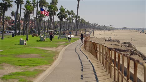 Surfers-walking-along-the-bike-path-in-Huntington-Beach,-California