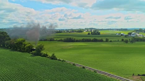 Eine-Drohnenansicht,-Die-Durch-Rauch-Geht-Und-An-Einem-Sonnigen-Sommermorgen-Amish-Ackerland-Sieht