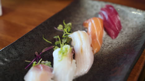 Line-of-colorful-nigiri-sushi-on-traditional-Japanese-sushi-platter,-slider-close-up-4K