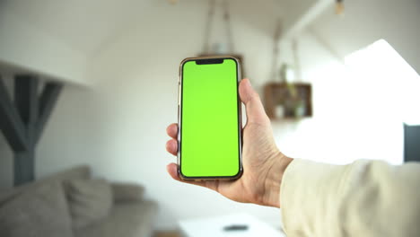 A-POV-of-a-man-holding-a-smartphone-with-greenscreen-in-vertical-standing-in-an-isolated-white-background-tapping-on-the-phone
