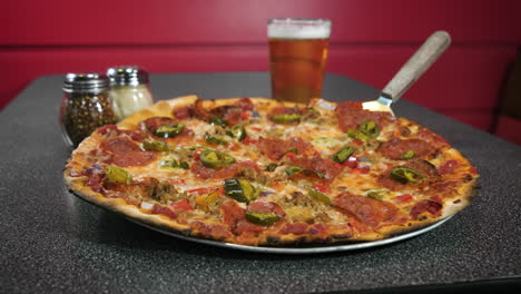 Klassische-Peperoni-Pizza-In-Grauer-Pizzeria-Tischplatte,-Gepaart-Mit-Pint-Bier,-Käse-Und-Paprika-Shakern-Auf-Rotem-Shiplap-Hintergrund,-4k
