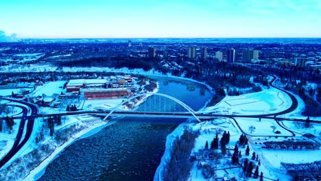 Winter-Antenne-Nach-Vorne-Fliegen-über-Den-Norden-Von-Saskatchewan-In-Richtung-Der-Walter-Dale-Brücke,-Während-Runde-Eisstücke-Den-Fluss-Hinuntergehen,-Aus-Der-Vogelperspektive,-Reflexion-Von-Gebäuden-An-Der-Küste,-Schneebedeckte-Parks2-3