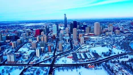 4k-winter2-2-aerial-forward-flyover-the-Rossdale-massive-empty-parking-lot-across-the-Edmonton-Prospects-Baseball-Club,-and-headed-to-the-snow-covered-downtown-core-over-Bellamy-Hill-RD-NW-windy-city