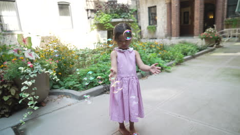 Asian-little-girl-popping-bubbles-in-the-courtyard-during-a-sunny-day
