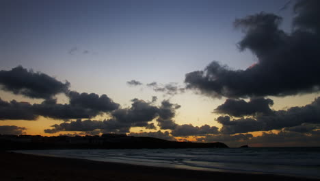Beautiful-Scenic-Sunset-to-Dusk-Time-Lapse-Along-the-Coastline-of-Newquay's-Fistral-Beach-with-Fast-Moving-Clouds-Across-the-Sky-in-Cornwall,-England,-UK