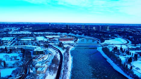 Aerial-winter-panoramic-flyover-the-North-Saskatchewan-River-from-North-to-South-in-between-the-Alberta-Treasury-Board-and-Finance,-the-Walter-Dale-iconic-white-bridge,-Kinsmen-Park,-109-St-NW-3-3
