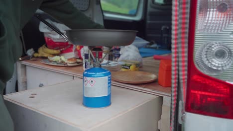 Man-Cooks-On-A-Portable-Camping-Stove-Gas-In-A-Campervan-Near-The-Mountains-Of-Donnamannen,-Norway