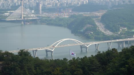 A-view-of-the-Han-River-and-the-Guri-Amsa-Bridge-in-Seoul,-South-Korea-as-seen-from-them-Acha-Mountain-hiking-trail-on-a-smoggy-day