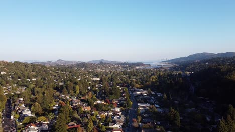 Aerial-view-of-a-quiet-and-wooded-town-in-the-hills-and-mountains-on-a-sunny-day