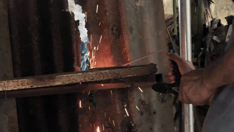 Professional-welder-employing-industrial-welding-machine-to-put-together-two-pieces-of-metal-creating-a-metalic-structure-as-part-of-his-daily-work-at-a-local-small-business