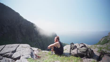 Mann-Wanderer-Sitzt-Und-Beugt-Seine-Knie-Auf-Einem-Felsvorsprung-Am-Berg-Donnamannen,-Nordland,-Norwegen