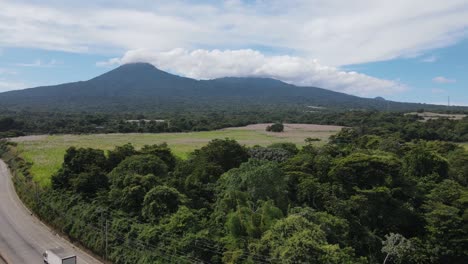 Panning-to-the-right-of-a-panoramic-view-of-an-area-with-a-lot-of-vegetation-and-a-tall-volcano-in-the-background