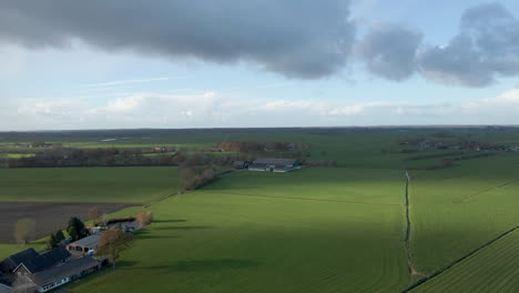 Aerial-of-a-distant-farm-surrounded-by-green-meadows