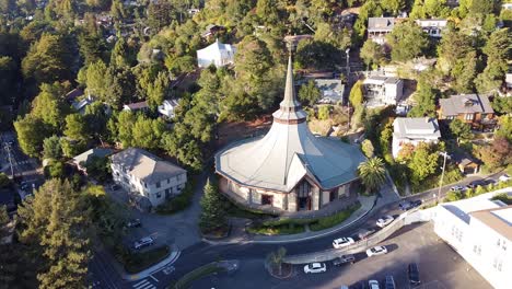 Aerial-view-of-a-modern-church-in-the-middle-of-the-town-with-lots-of-trees-and-greenery-at-the-rising-sun