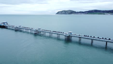 Llandudno-pier-historic-Victorian-wooden-boardwalk-seaside-landmark-aerial-view-wide-left-pan-shot