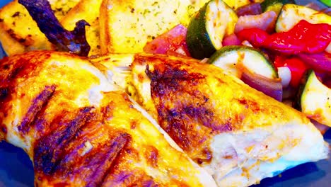 BBQ-rotisserie-closeup-plate-if-chicken-breasts-legs-halves-and-quarters-with-grill-marks-mixed-with-toasted-garlic-bread-with-seasoning-and-grilled-peppers-onions-zucchini-on-a-ceramic-plate-at-360
