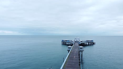 Llandudno-pier-historic-Victorian-wooden-seaside-landmark-aerial-view-flying-down-boardwalk