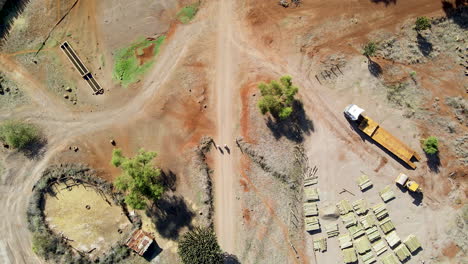 Top-down-aerial-of-two-people-walking-over-path-near-farm-and-construction-site-in-rural-Kenya