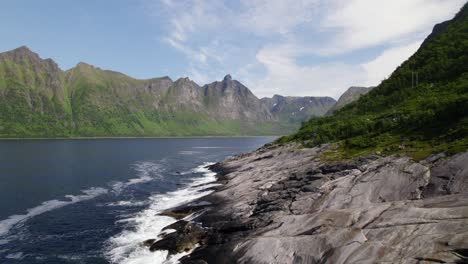 Fliegen-Parallel-Zum-Felsigen-Strand-In-Der-Bucht-Mit-Bergkette-Im-Hintergrund-In-Norwegen-Auf-Der-Insel-Senja