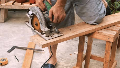 Skillfull-carpenter-cuts-with-an-industrial-circular-saw-machine-a-piece-of-wood-to-create-beautiful-forniture-in-his-outdoor-traditional-workshop-small-business