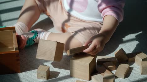 Baby-playing-with-toddler-wooden-blocks-at-the-balcony-staking-up-one-on-another---educational-game-for-kids