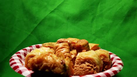 4k-Loop3-3-Baklava-dessert-assorted-variation-of-bite-sized-sweets-rotating-120-degree-plate-with-green-screen-back-drop-on-a-checked-picnic-style-paper-plate-in-red-and-white