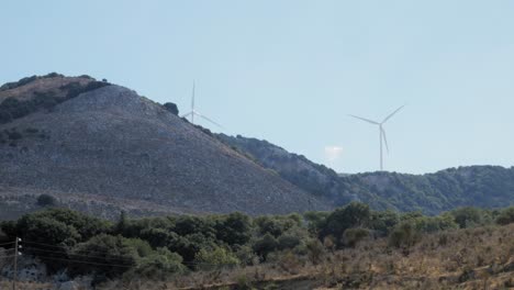 Fernsicht-Auf-Windkraftanlagen,-Die-Hinter-Hügeln-Auf-Der-Insel-Agia-Kiriaki-In-Griechenland-Alternative-Energie-Erzeugen