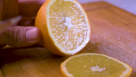 View-of-hand-cutting-an-orange-slice-on-a-wooden-board