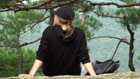 Back-View-Of-A-Girl-In-Cap-Sitting-And-Admiring-Nature-In-The-Achasan-Mountain