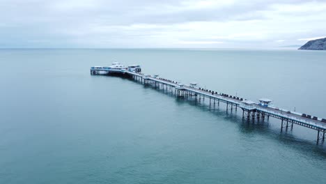 Llandudno-pier-historic-Victorian-wooden-boardwalk-seaside-landmark-aerial-view-descending-to-ocean