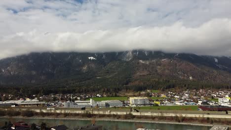 Drone-Vuela-Sobre-Brixlegg-En-Tirol,-Montañas-Con-Nubes-Y-La-Posada-Del-Río