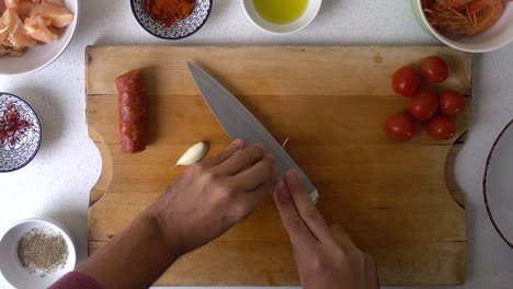 Top-down-cooking-video,-male-hands-peeling-garlic-with-back-of-knife