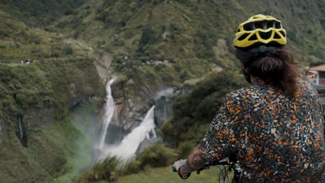 Biker-looking-to-the-beautiful-waterfalls-during-biking-route-tour-in-Baños-Ecuador
