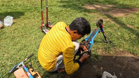 Asian-man-repairs-children-bicycle-in-garden