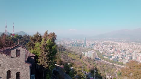 Panoramic-view-of-Santiago-from-San-Cristobal-hilltop-and-Greenery-metropolitan-park,-Chile---Aerial-Upwards