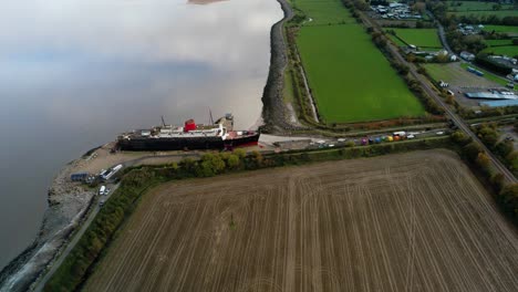 TSS-Duke-of-Lancaster-abandoned-railway-steamer-ship-docked-in-Mostyn-Docks,-River-Dee,-North-Wales---aerial-drone-shot